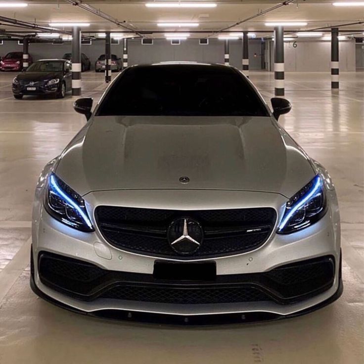 the front end of a silver car in a parking garage