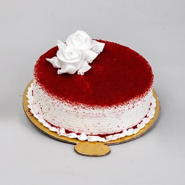 a red velvet cake with white frosting and a rose on top, sitting on a gold platter