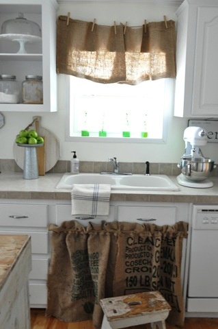 a kitchen with a sink, window and some burlap bags on the counter