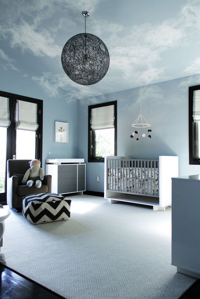 a baby's room with blue walls and clouds painted on the ceiling is shown