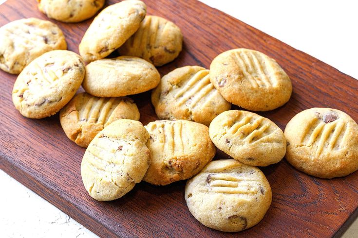 a wooden cutting board topped with cookies on top of a table next to a knife