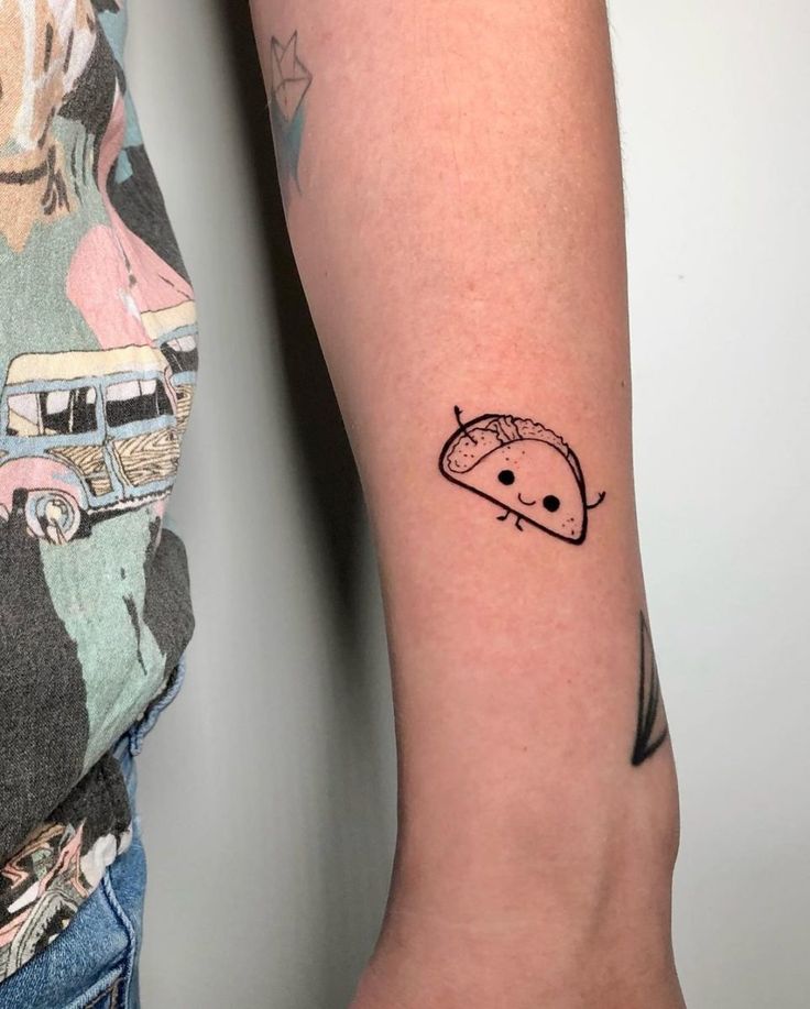 a person with a small tattoo on their arm that has an image of a flying saucer