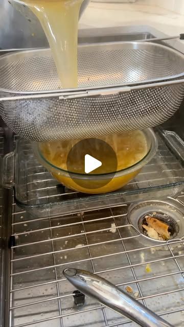 a bowl filled with liquid sitting on top of a metal counter next to a sink