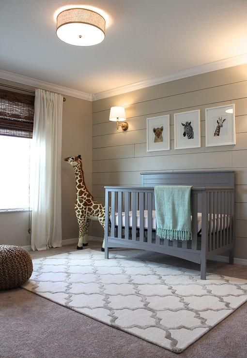 a baby's room with a giraffe standing next to the crib