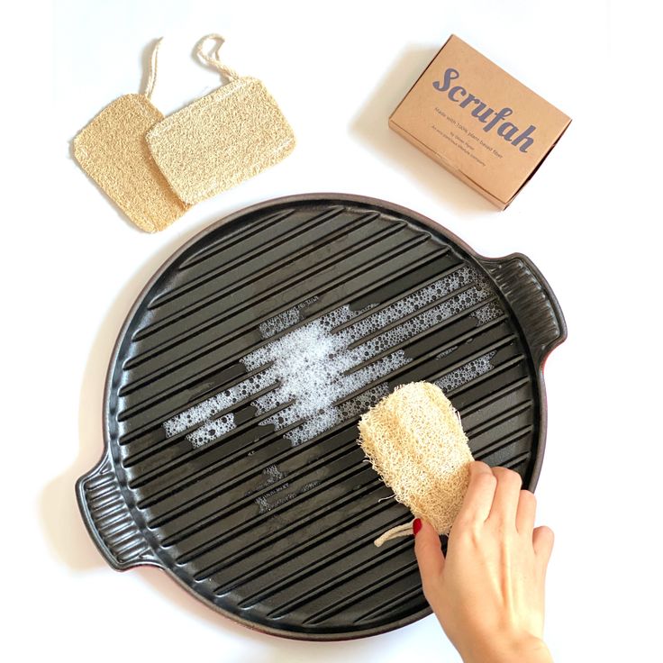 a person is cleaning a grill with a sponge on it and some other items nearby