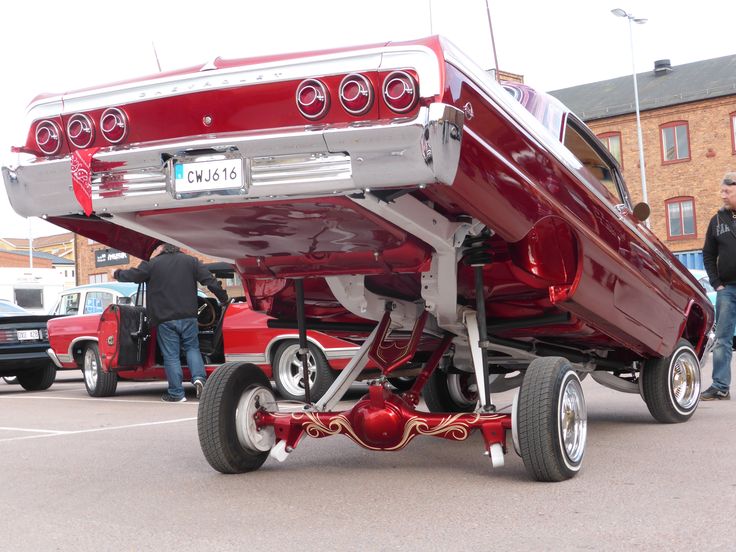 the rear end of a red classic car parked in a parking lot