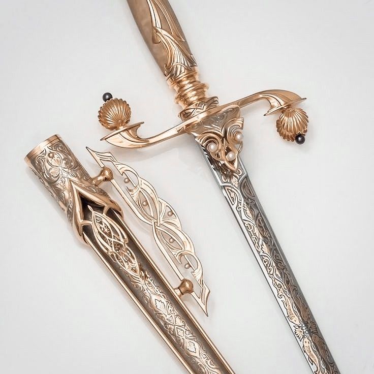 two swords with intricate designs on them, one is gold and the other is silver