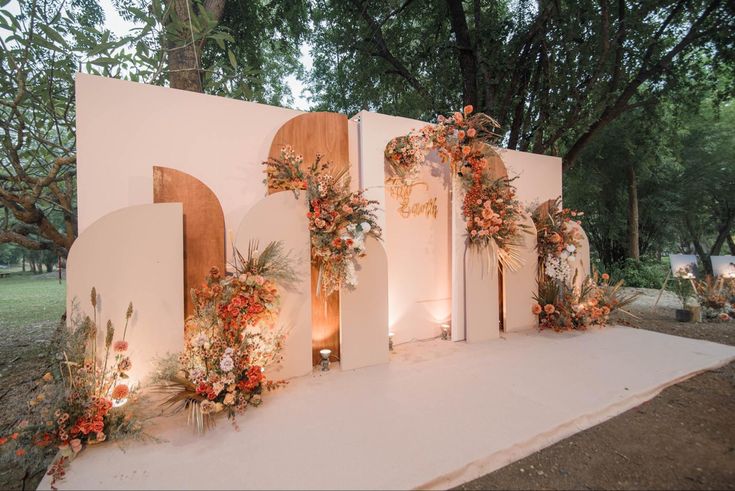 an outdoor ceremony setup with flowers and greenery on the wall, surrounded by candles