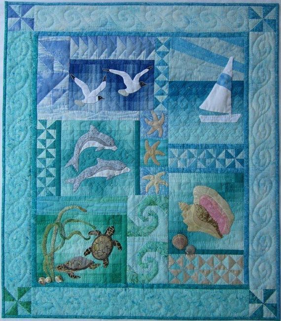 a quilted wall hanging with sea animals and seashells on blue fabric,