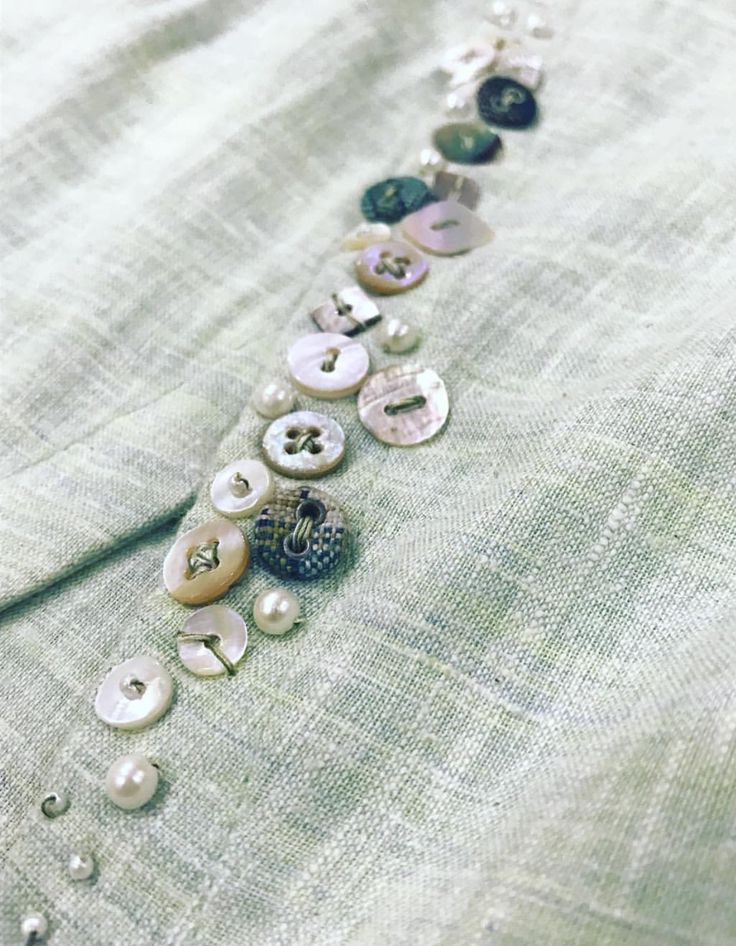 buttons are arranged in the shape of an arrow on top of a green shirt with silver beads