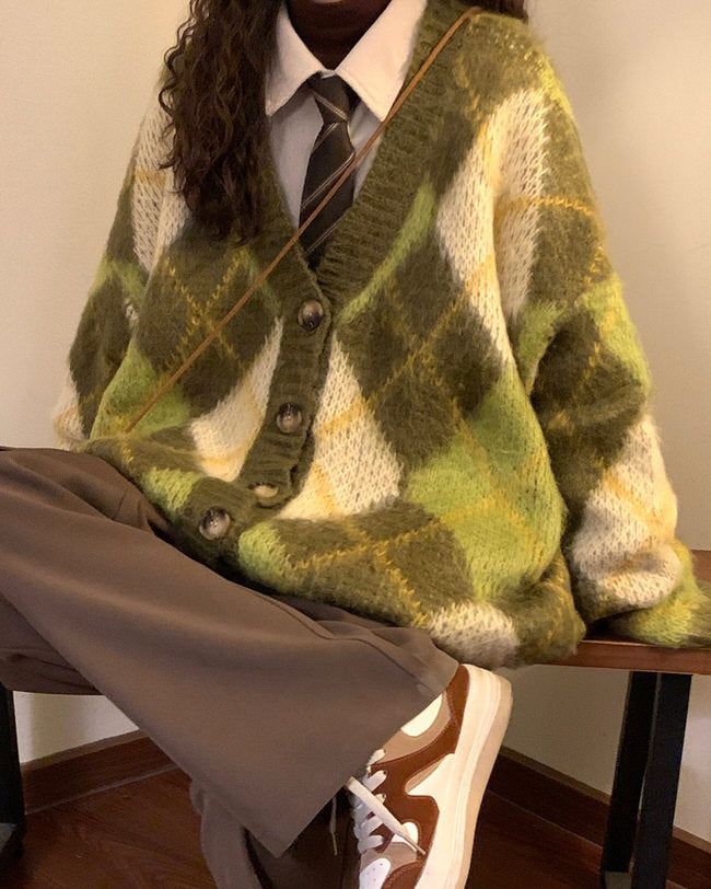 a woman sitting on top of a wooden bench wearing a sweater and tie