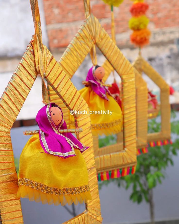 some yellow and pink decorations hanging from strings in the shape of people on stilts