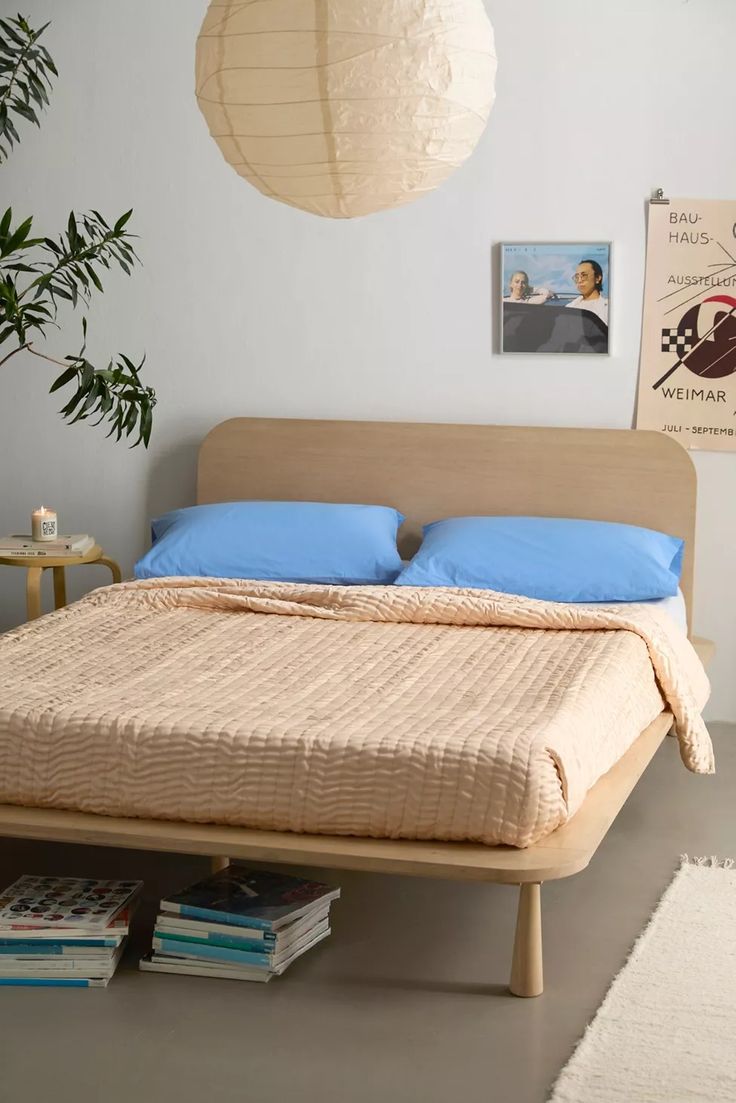 a bed with blue pillows and blankets on top of it next to a potted plant