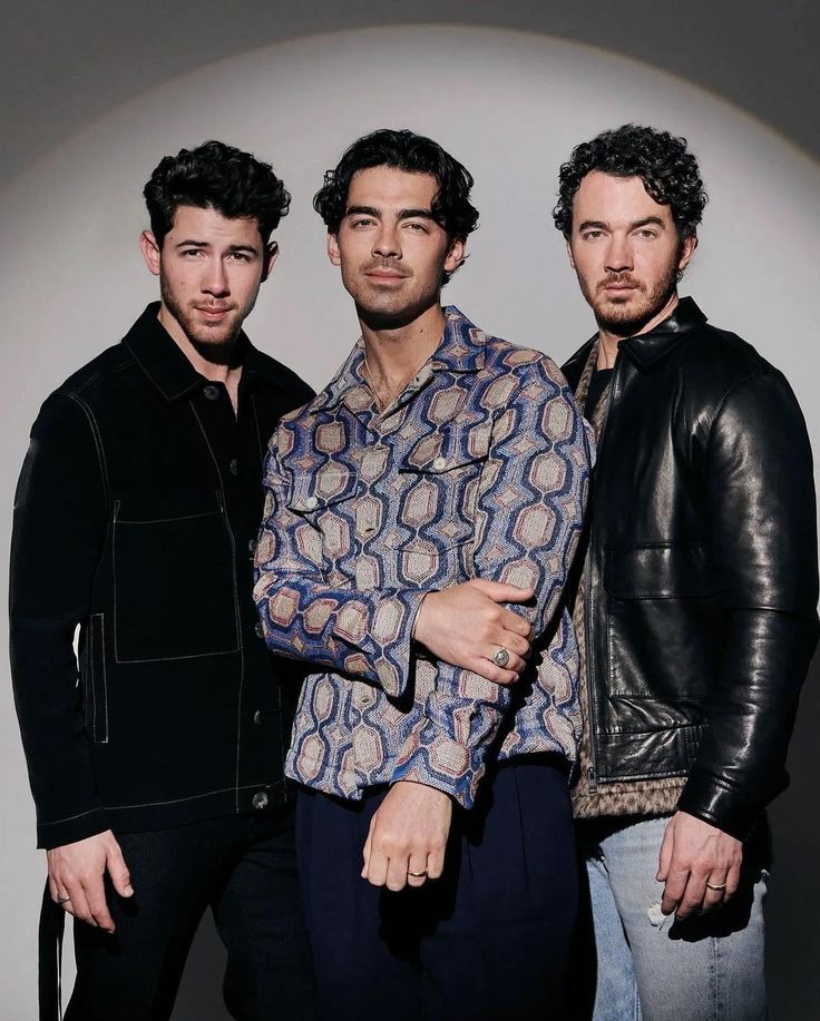 three men standing next to each other in front of a white background