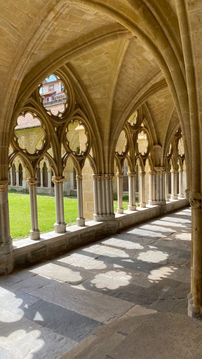 the inside of an old building with columns and arches on both sides that are lined with grass