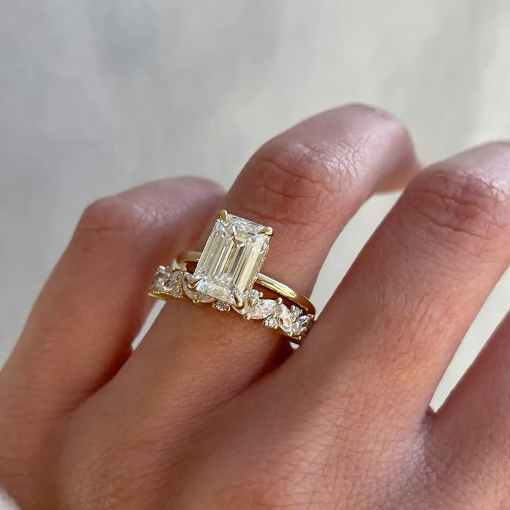 a woman's hand with a diamond ring on top of her finger and an engagement band