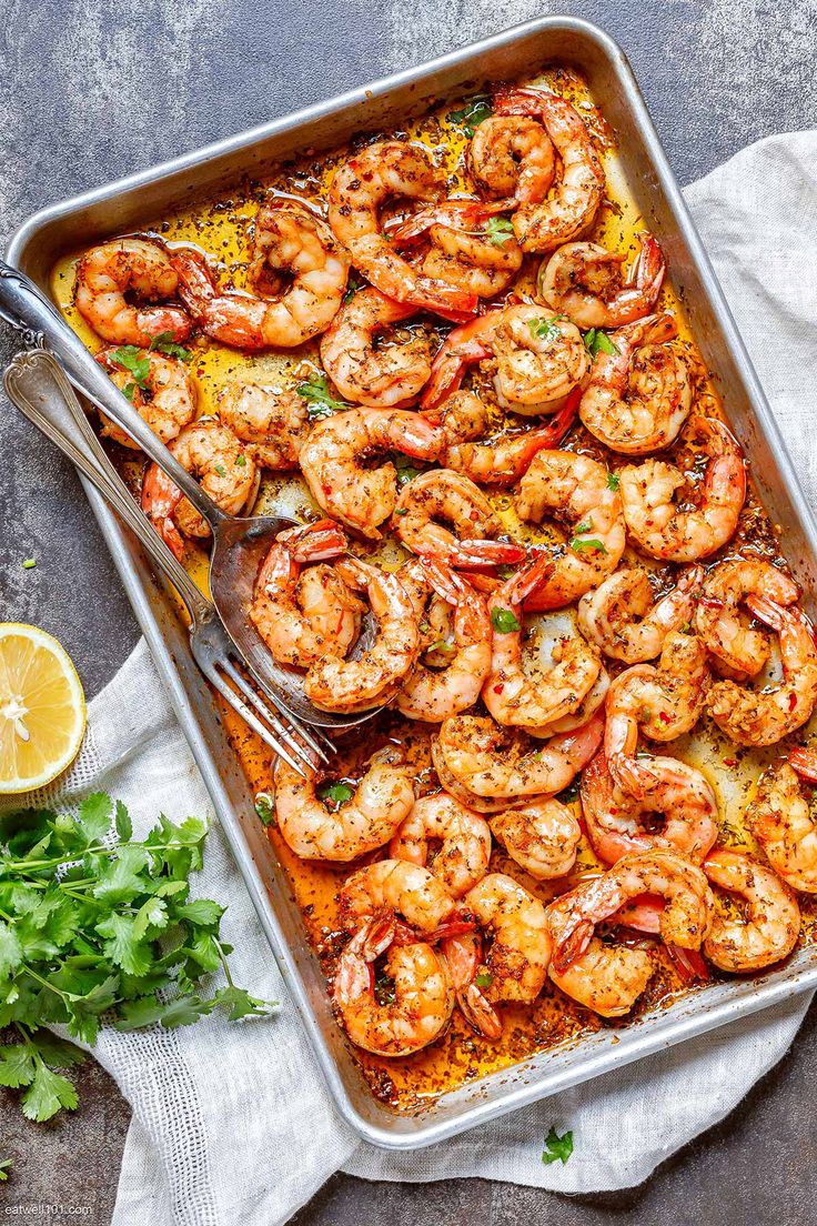 a pan filled with cooked shrimp and garnished with parsley on the side