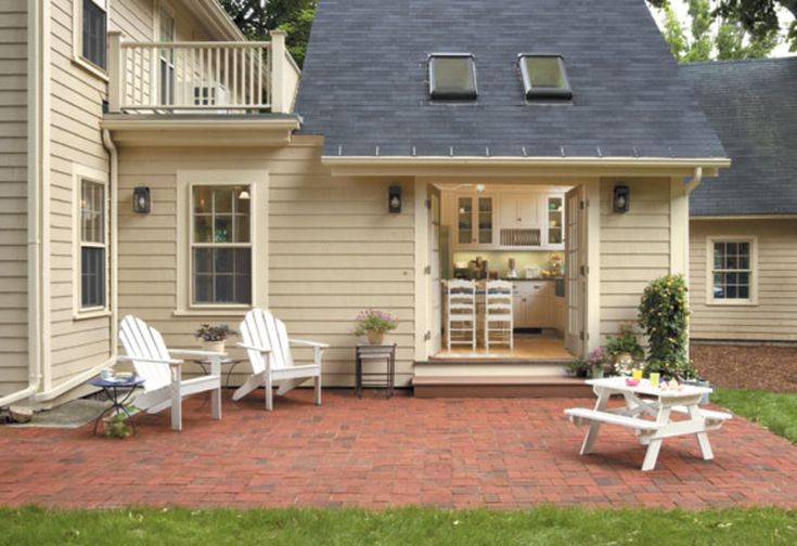 a small house with white lawn chairs in front of it and an open patio area