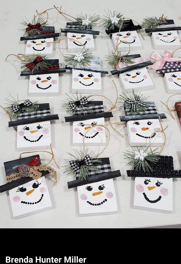 several snowmen are hanging from small cards on a table with pine cones and twine