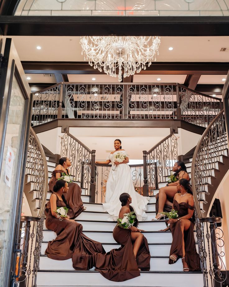 a bride and her bridal party sitting on the stairs