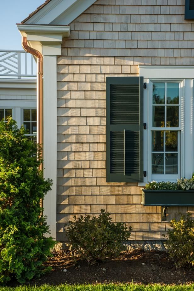 a house with shutters open and plants in the window