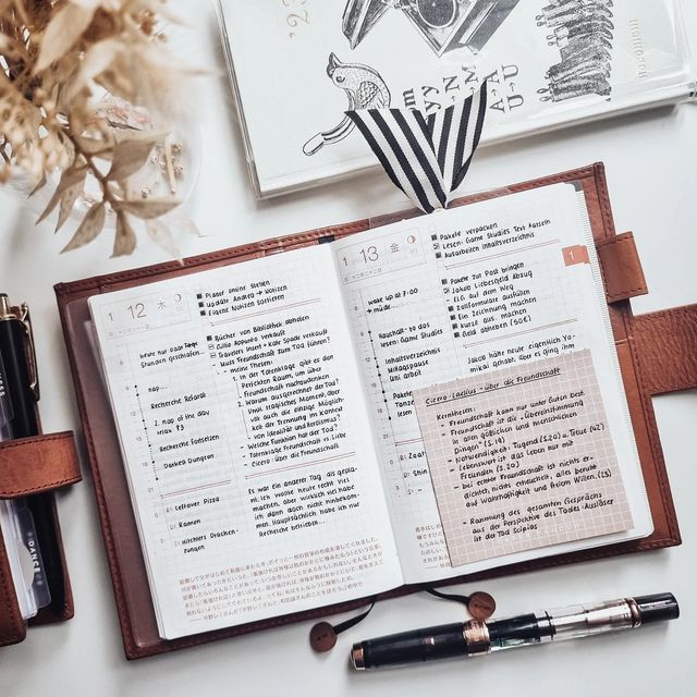 an open book sitting on top of a desk next to a pen and other items