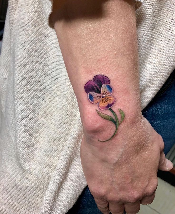 a woman's arm with a flower tattoo on the left side of her wrist