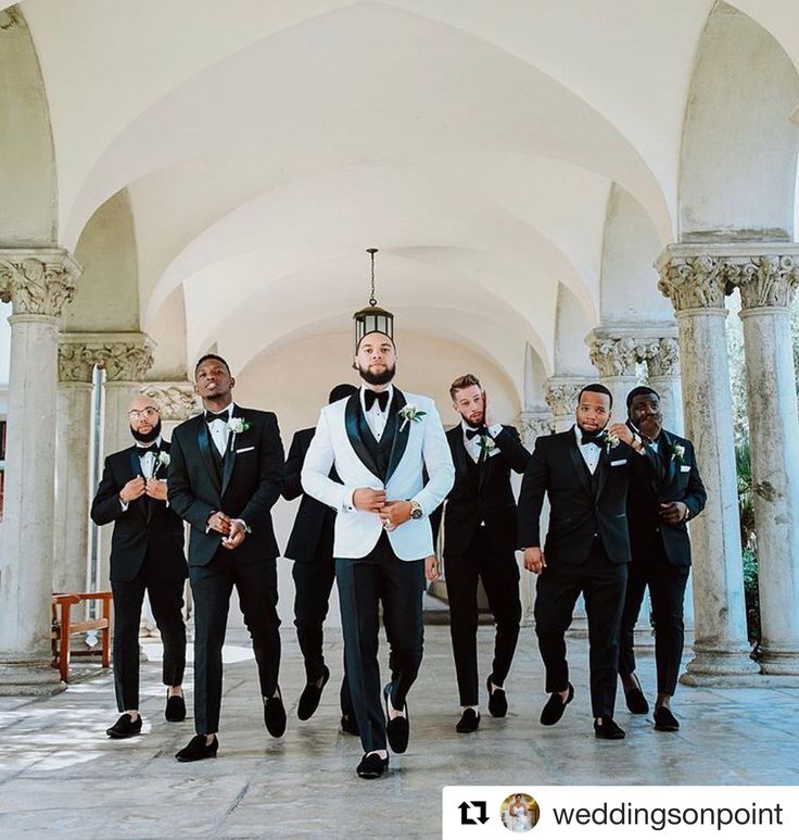 a group of men in tuxedos standing next to each other under an archway