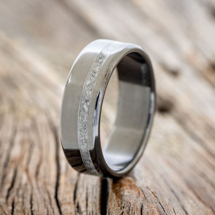 a wedding ring that is sitting on top of a wooden table with wood grain in it