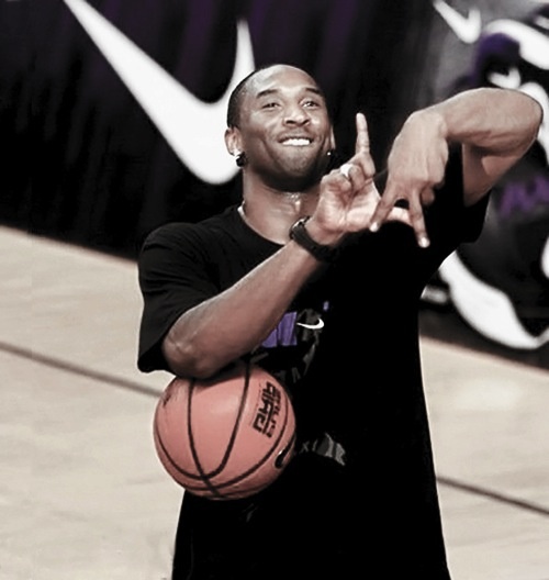 a man holding a basketball in his right hand and pointing to the side with both hands