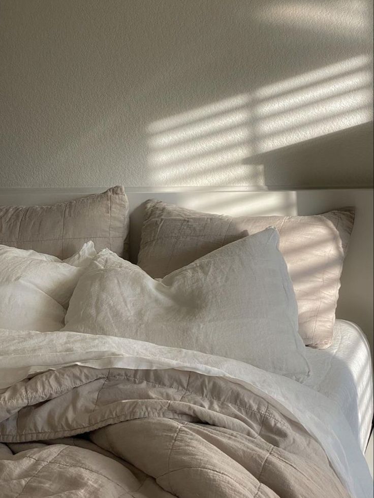 an unmade bed with white sheets and pillows