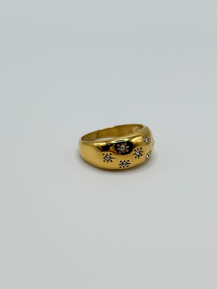 a yellow gold ring with small diamonds on the outside and in the middle, sitting on a white surface