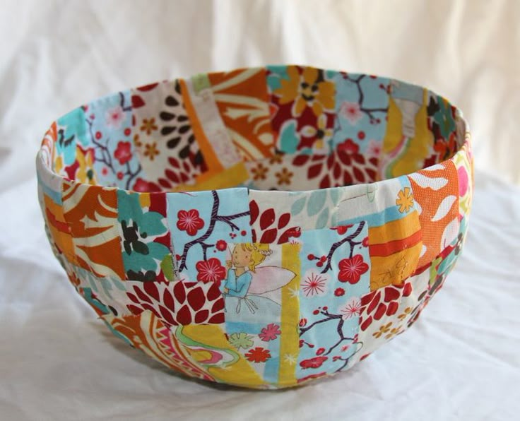 a colorful flowered bowl sitting on top of a white tablecloth covered table cloth