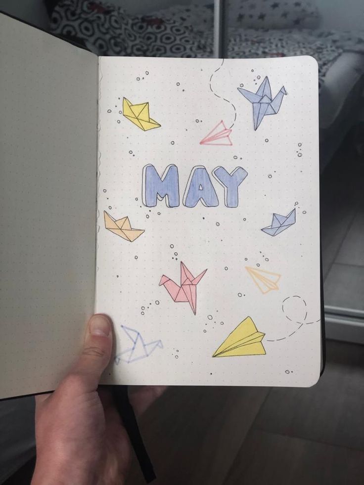 someone is holding up a notebook with origami on it and the word may written in blue ink