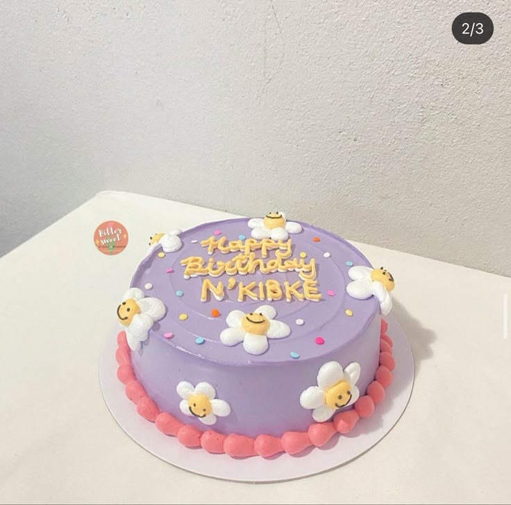 a purple birthday cake with flowers on the top and happy birthday n'kikike written on it