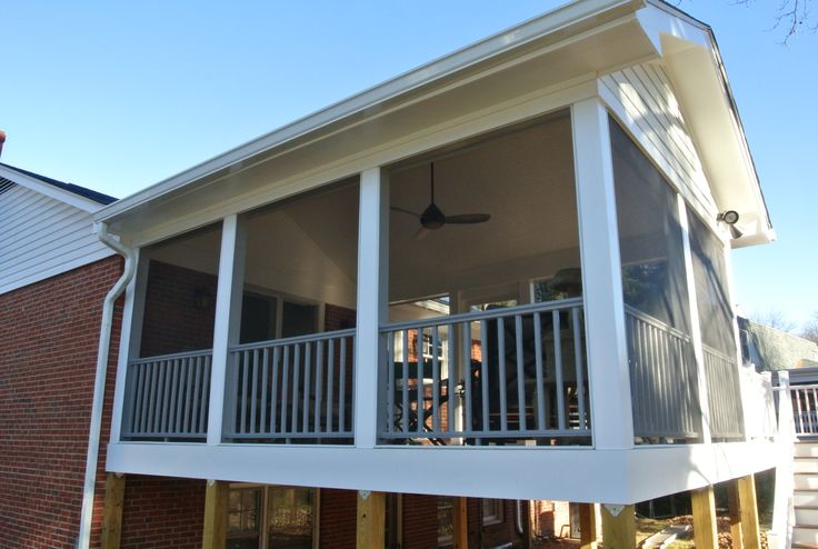 a balcony with white railing and black ceiling fan