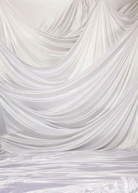 a bed with white sheets on top of it in front of a curtained wall