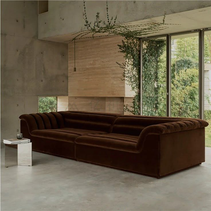 a large brown couch sitting inside of a living room next to a tall glass window