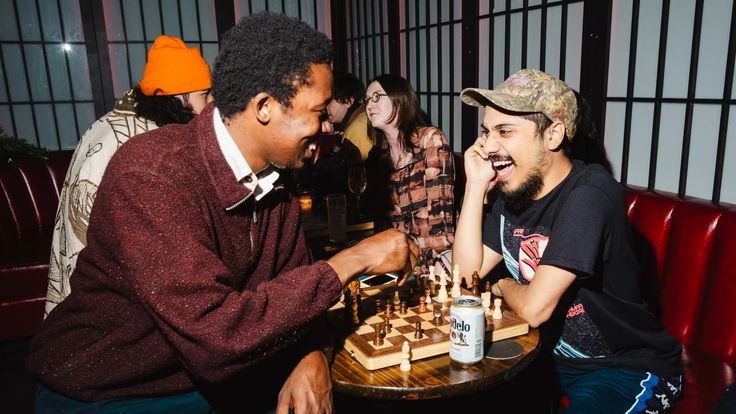 two men sitting at a table playing chess