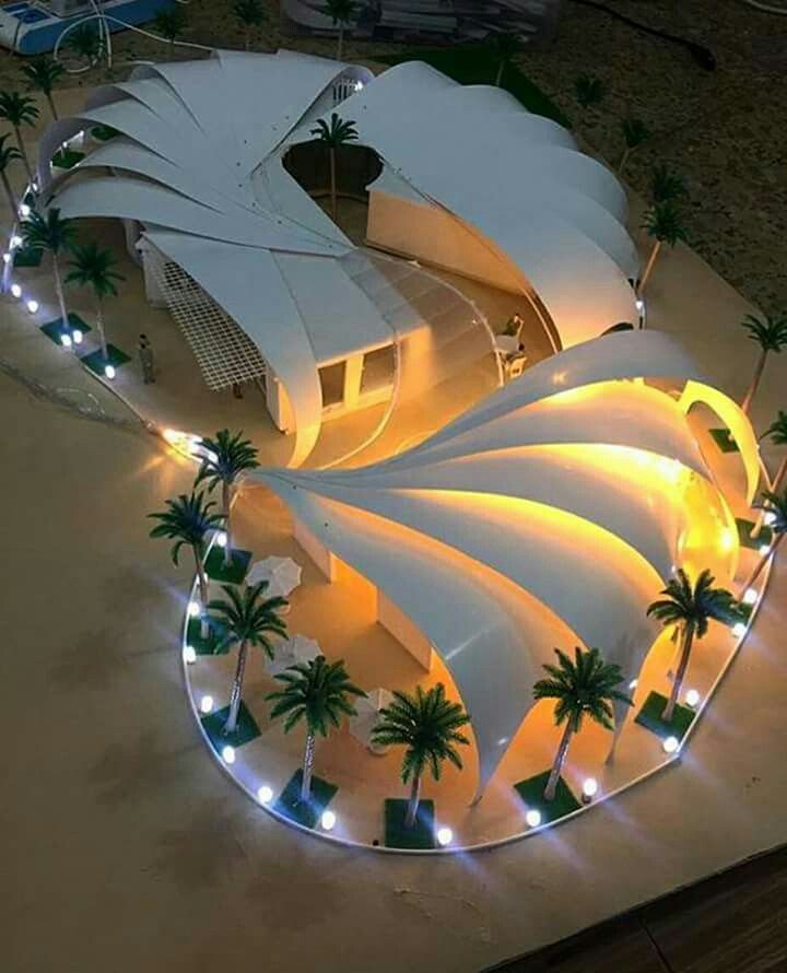 an aerial view of a building with palm trees on the ground and lights around it