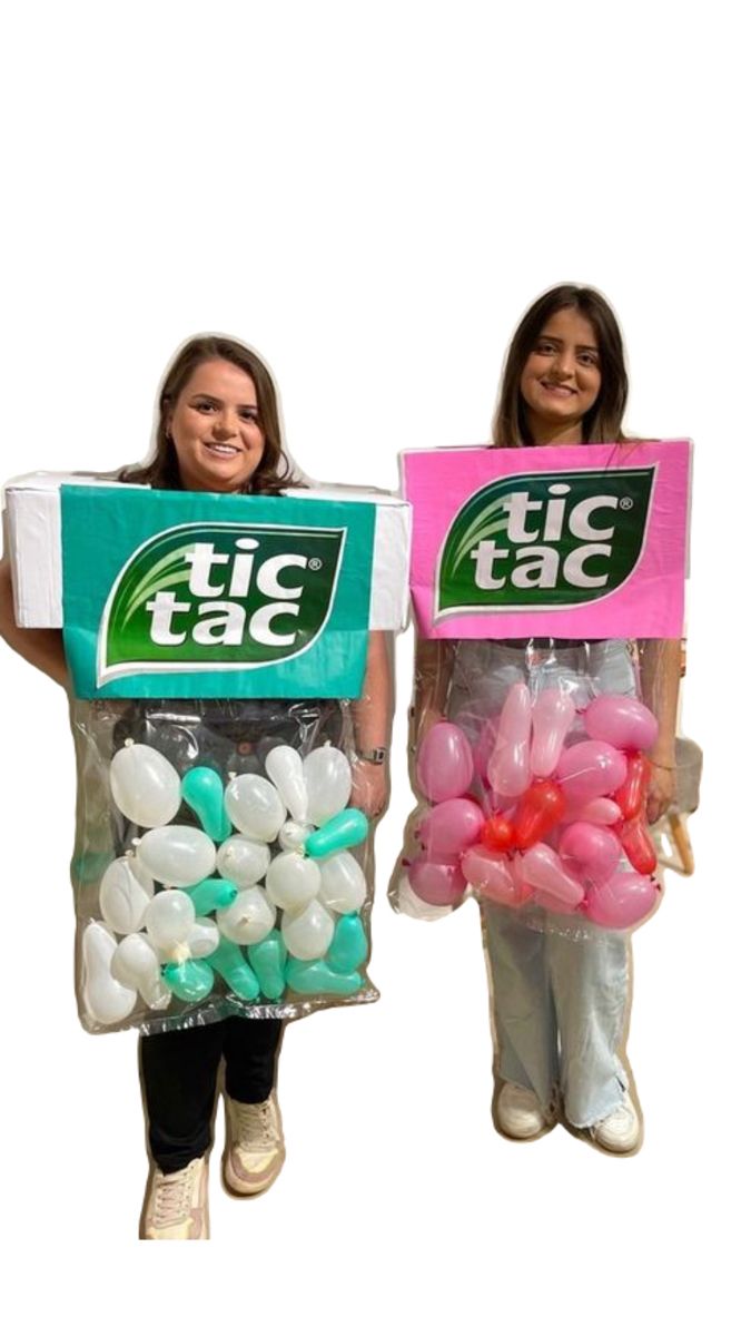 two girls are holding up giant bags of balloons