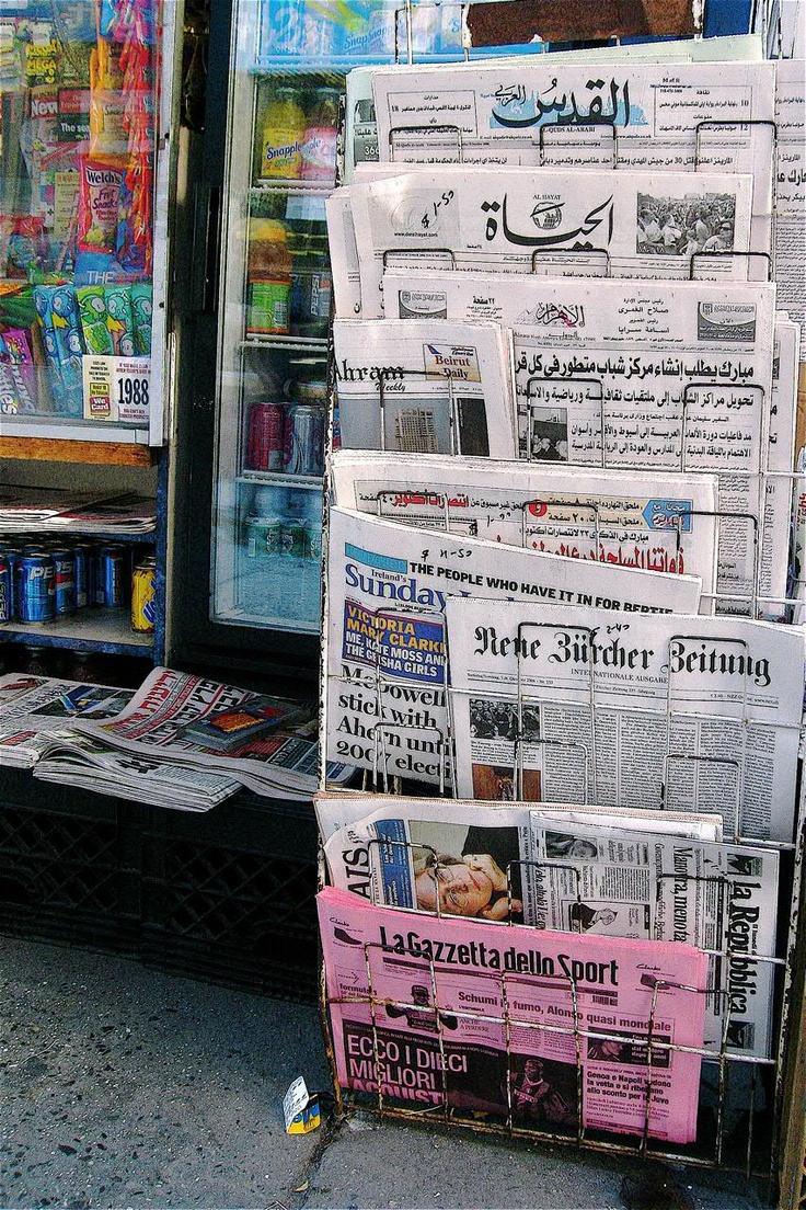 newspapers are stacked on top of each other in front of a newspaper stand