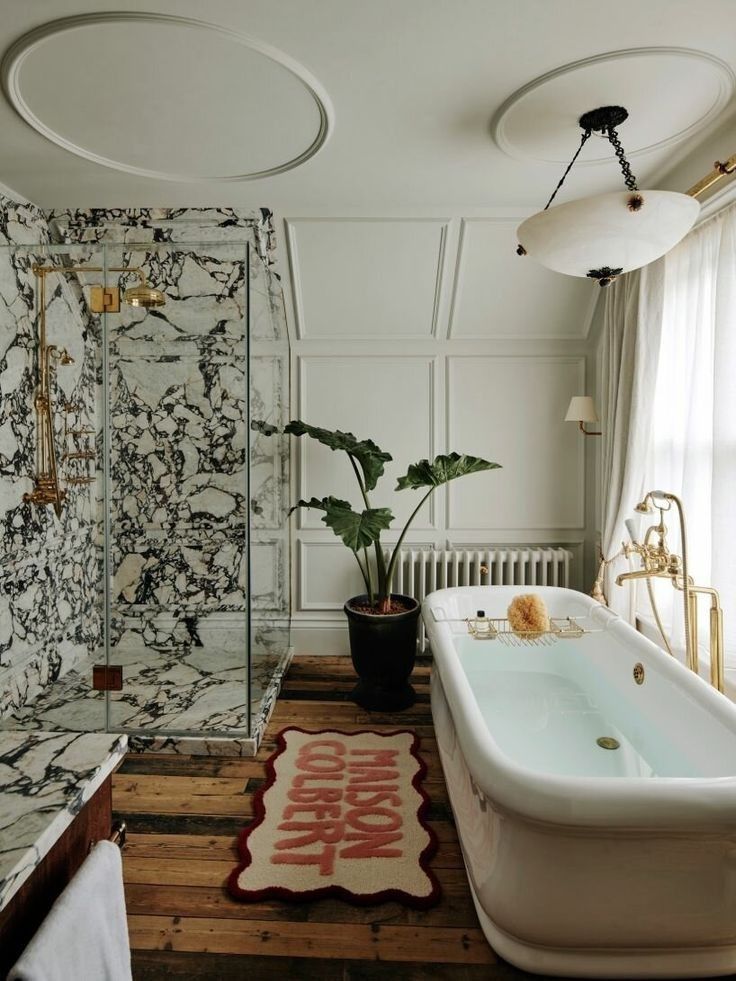 a bath tub sitting next to a shower in a bathroom on top of a wooden floor