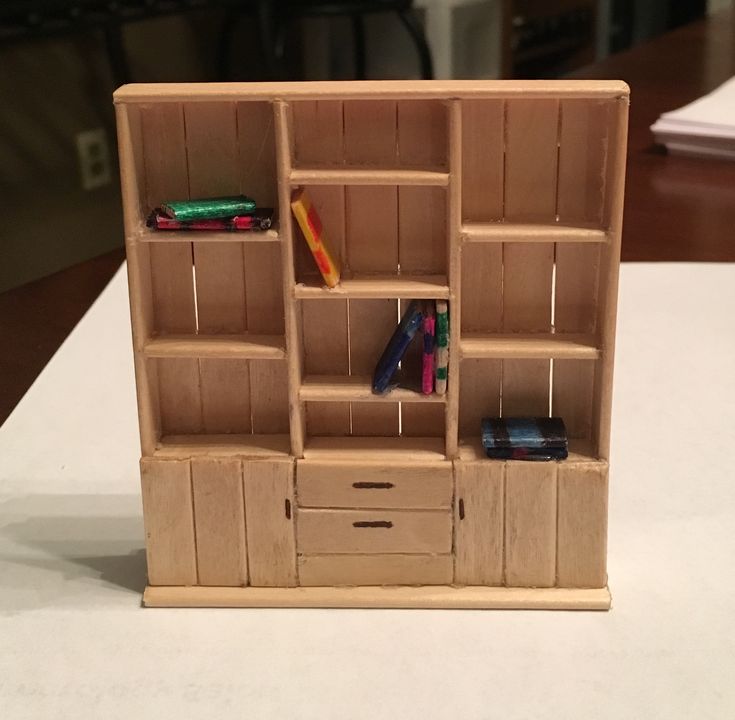 a toy book shelf with drawers and books on it's sides sitting on a table