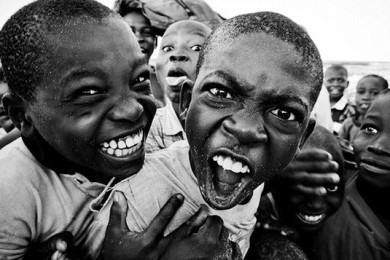 two young boys with their mouths open in front of a group of other children smiling