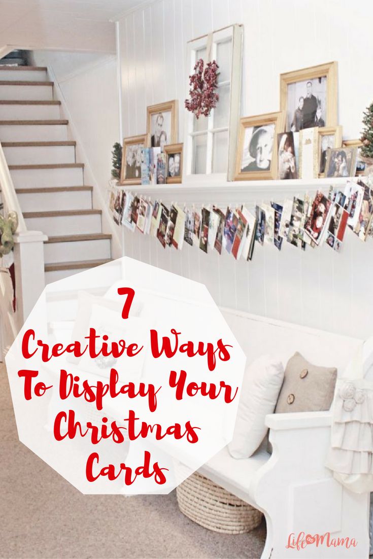 a living room with stairs and pictures hanging on the wall, in front of a christmas tree