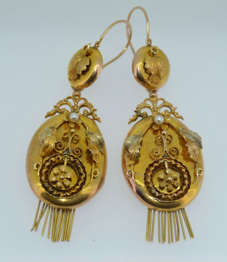 A lovely pair of Original Victorian-era earrings. These earrings date from the late 1800s. They are crafted from 14K Yellow and Rose Gold. The earrings are day and night, meaning you can adorn the ear with the button tops alone or add the massive body for a very dramatic look. These earrings instantly reminded me of lockets. The body is an oval shape with a gold fringe at the bottom. The fronts of the body are decorated with applied fine gold work in Rose Yellow and green gold. They are applied Victorian Style Drop Pearl Earrings, Vintage Yellow Gold Drop Pearl Earrings, Antique Earrings With Historical Design For Ceremonial Occasions, Vintage Yellow Gold Earrings For Evening, Vintage Yellow Gold Evening Earrings, Antique Drop Earrings With Historical Design, Antique Earrings With Historical Design, Antique Jewelry With Historical Design Drop Earrings, Antique Jewelry Drop Earrings With Historical Design