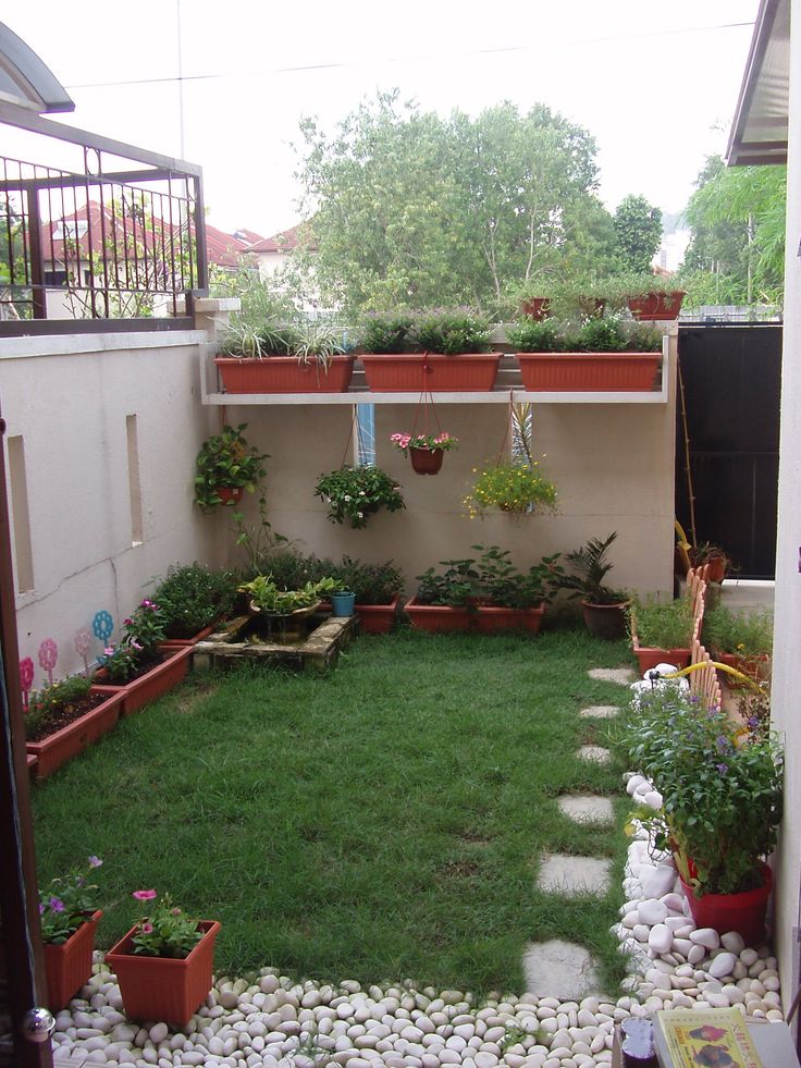 a small garden with lots of potted plants and rocks in the grass next to it