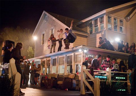 a group of people standing on the roof of a house at night with their arms in the air