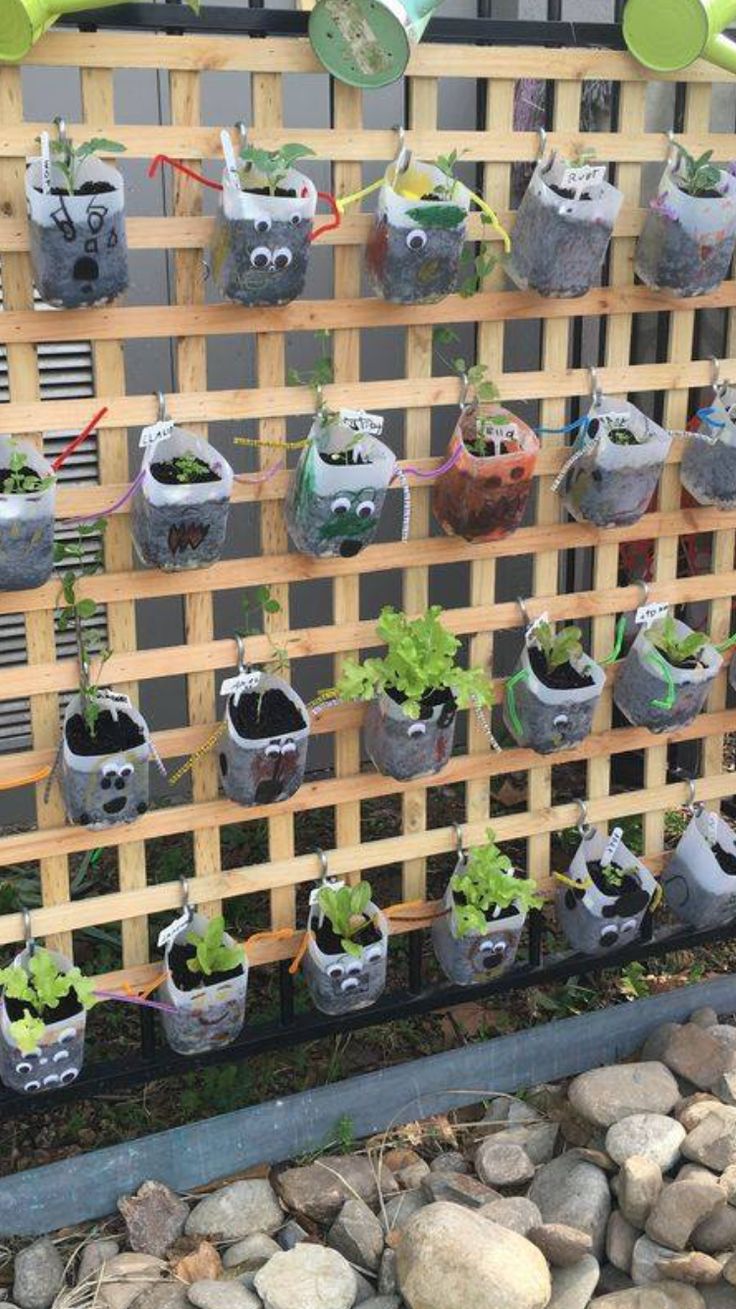 an outdoor garden with plants growing in pots and watering hoses attached to the fence